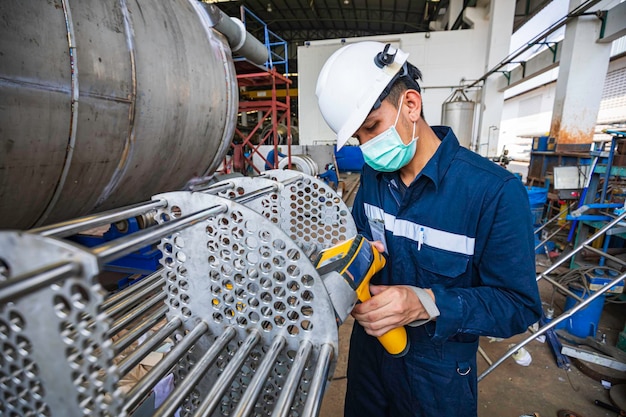 Male worker inspecting surface on heat exchanger tube bundle industrial construction warehouse positive