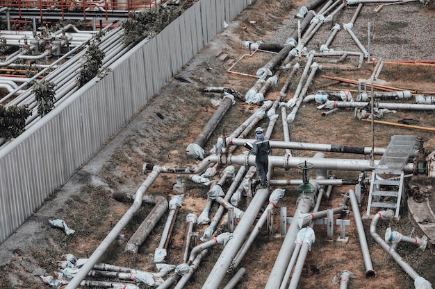 Фото Инспекция рабочего мужчины при резке стальных длинных труб и трубных локтей на новой строительной станции нефтяного завода во время очистки клапана трубопровода визуальной проверки записи