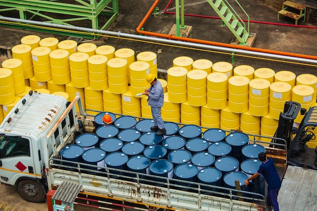 Male worker inspection record drum oil stock barrels yellow and blue vertical or chemical for transportation truck male in the industry.