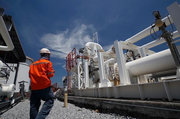 Ispezione del lavoratore di sesso maschile su tubi lunghi in acciaio e gomito del tubo nella fabbrica di petrolio della stazione durante la valvola di raffineria del registro di controllo visivo