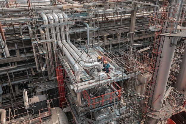 Photo male worker inspection at steel long pipes and pipe elbow in station oil factory fin fan during refinery valve of visual check record pipeline heat exchanger