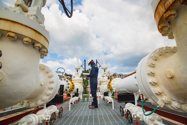 Male worker inspection at steel long pipes and pipe elbow in station oil factory during refinery valve of visual check record pipeline oil and gas industry.