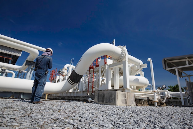 Male worker inspection at steel long pipes and pipe elbow in station oil factory during refinery valve of visual check record pipeline oil and gas industry