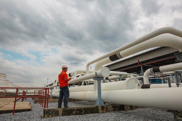 Male worker inspection at steel long pipes and pipe elbow in station oil factory during refinery valve of visual check record pipeline