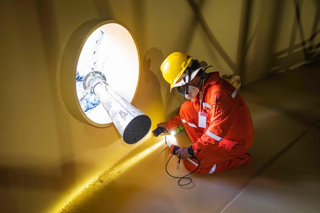 Foto ispezione del lavoratore di sesso maschile in una prova di colore della verniciatura superficiale del serbatoio della piastra inferiore della torcia di controllo visivo