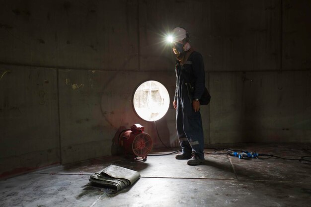 Ispezione del lavoratore di sesso maschile sostanze chimiche visive in acciaio inossidabile ventilatore aria fresca nello spazio limitato del serbatoio di stoccaggio