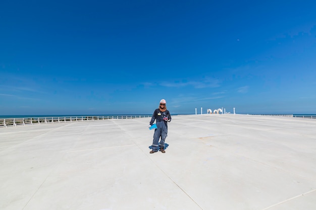 Male worker inspection visual roof storage tank oil  city and blue sky