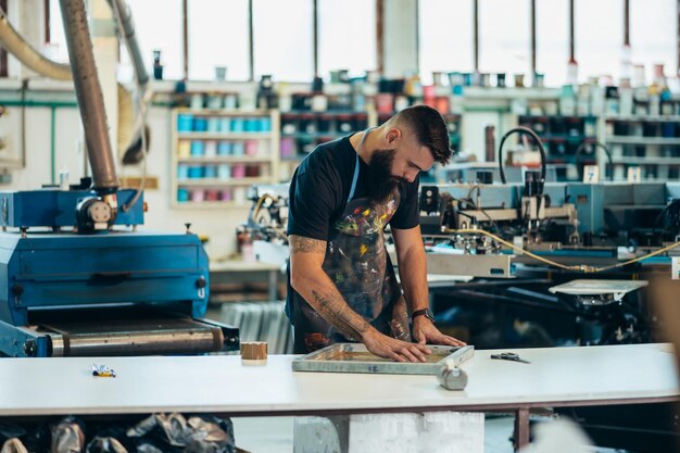 Lavoratore maschio che prepara film per serigrafia in un'officina