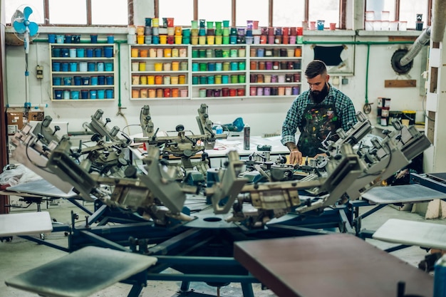 Male worker pressing ink on frame while using the printing
machine in a workshop