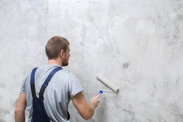 A male worker primes the wall with a roller for better grip