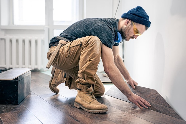 Foto un lavoratore di sesso maschile mette il pavimento in laminato sul pavimento