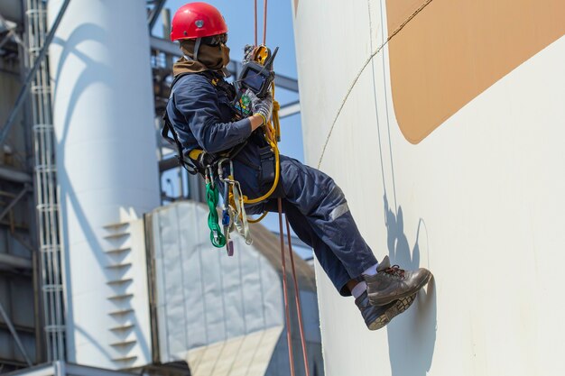 Male worker rope access height safety inspection of thickness\
storage oil and gas tank industry