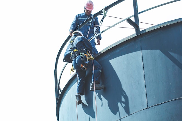 Male worker rope access height safety inspection of thickness\
storage oil and gas tank industry