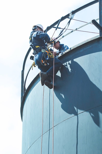 Male worker rope access height safety inspection of thickness storage oil and gas tank industry