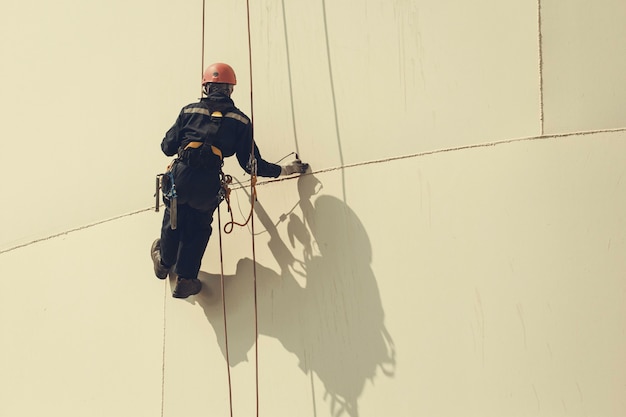 Male worker rope access height safety inspection of thickness storage oil and gas tank industry