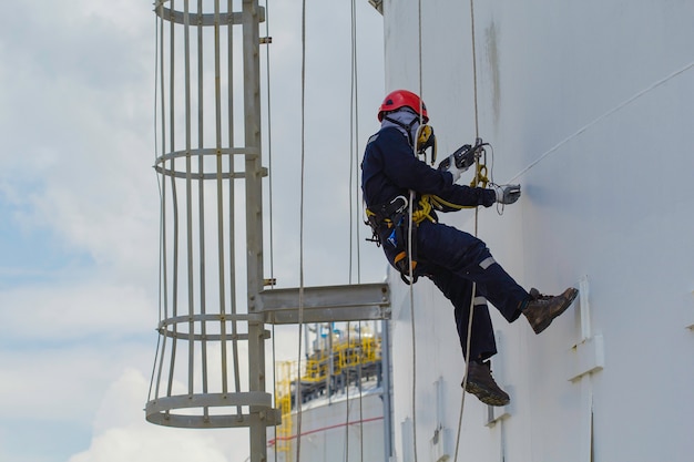 Male worker rope access height safety inspection of thickness\
storage oil and gas tank industry