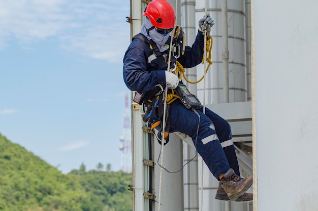 Male worker rope access height safety inspection of thickness storage oil and gas tank industry