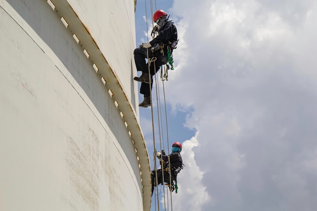 Male worker rope access height safety inspection of thickness\
storage oil and gas tank industry