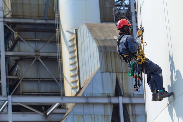 Male worker rope access height safety inspection of thickness storage oil and gas tank