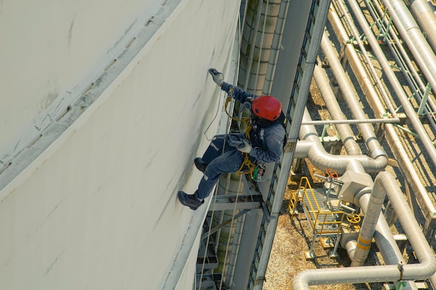 Male worker rope access height safety inspection of thickness storage oil and gas tank