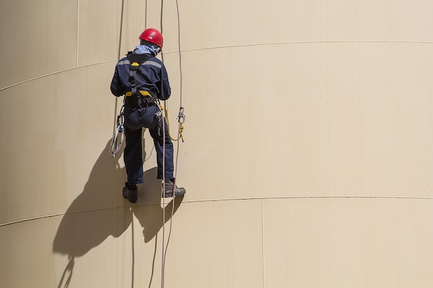 Male worker rope access  inspection of  thickness shell plate storage tank oil industry.