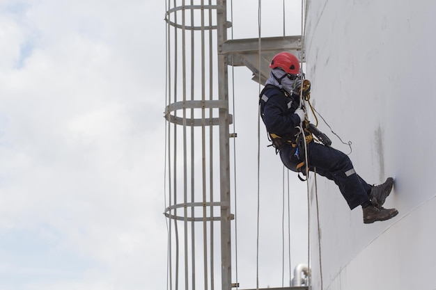 Male worker rope access inspection of thickness storage tank industry close to stairway