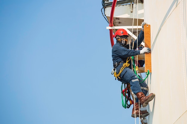 Male worker rope access inspection of thickness storage tank industry.