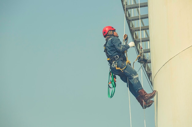 Male worker rope access inspection of thickness storage tank\
industry