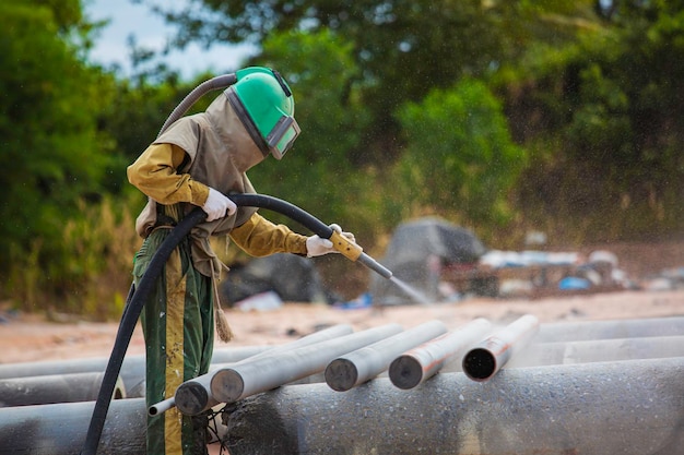 Male worker Sand blasting process cleaning pipeline surface