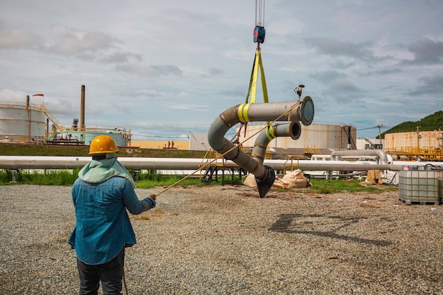 Male worker the slinger at crane work. Unloading by the crane of the production pipeline oil and valve equipment.