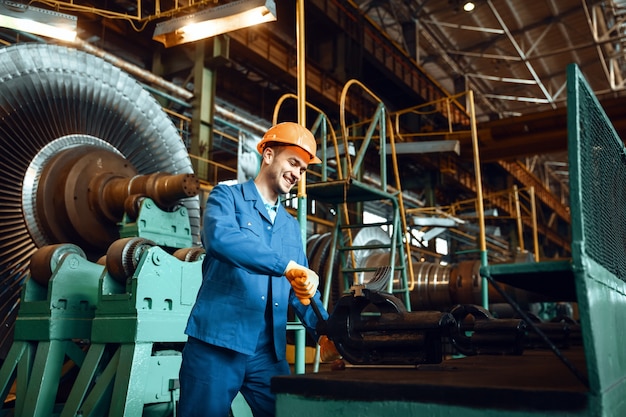 Male worker squeezes detail in a vise on factory, turbine impeller with vanes