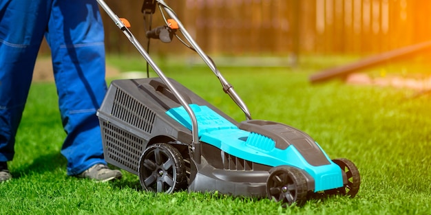 Male worker on the street working on mowing the lawn with the help of a modern lawn mower