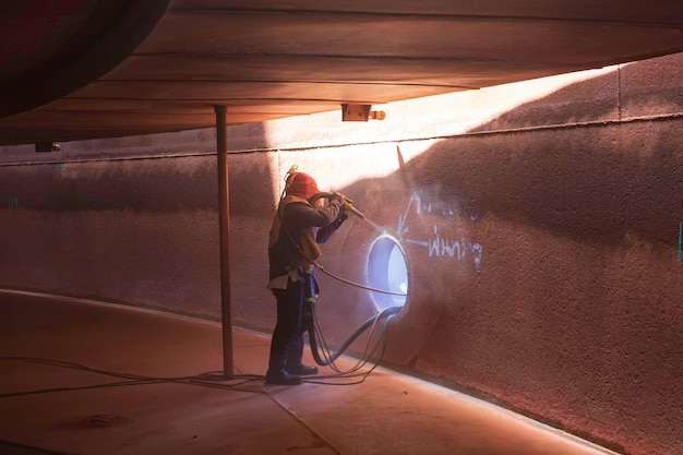 Male worker surface corrosion plate preparation by sand blasting of tank internal oil