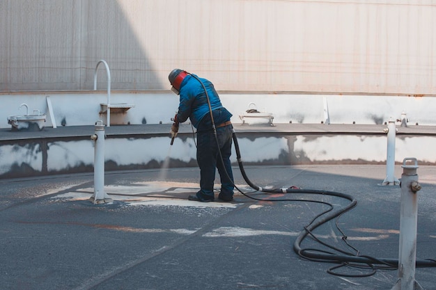 Male worker surface corrosion roof plate preparation by sand blasting of tank