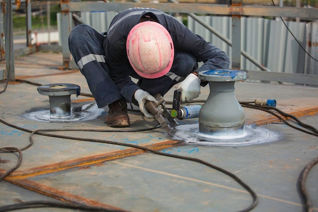 Male worker test nozzle tank butt weld carbon roof plate of storage tank oil background white contrast of magnetic field