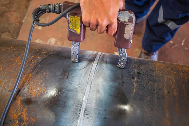 Male worker test steel pipeline butt weld carbon background white contrast of magnetic field test