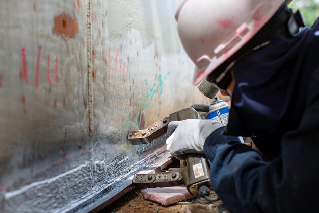 Мужчина-рабочий тестирует стальной бак встык, углеродистая пластина корпуса резервуара для хранения масла, магнитное поле