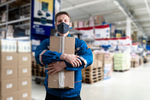 A male worker in uniform holding box, shipping delivery process, business distribution