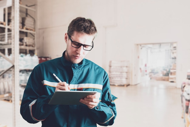 Un lavoratore di sesso maschile in uniforme che tiene e usa un tablet