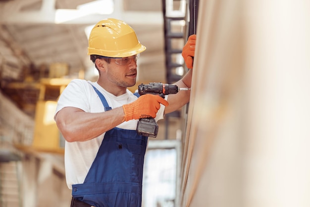 Male worker using cordless electric drill at construction site