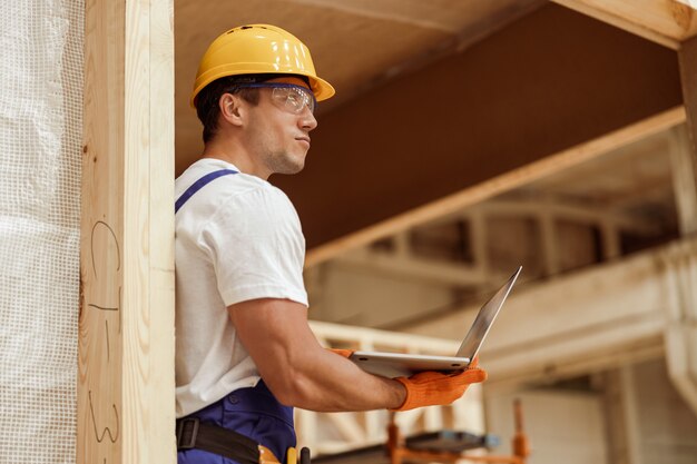 Male worker using laptop at house building construction site