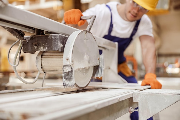 Male worker using sawing machine in workshop