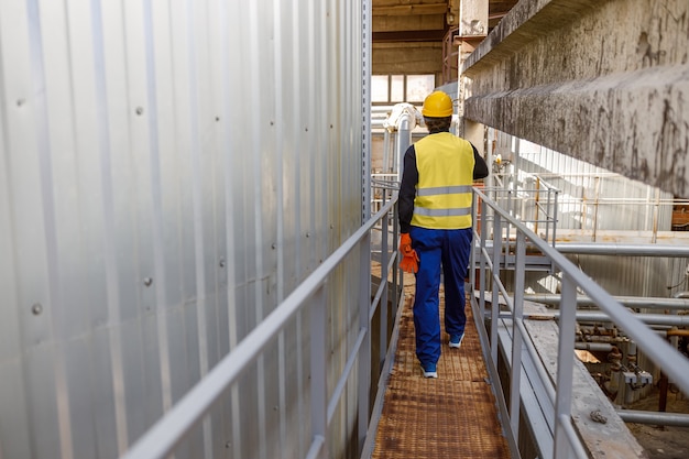 Male worker walking on metal bridge at factory