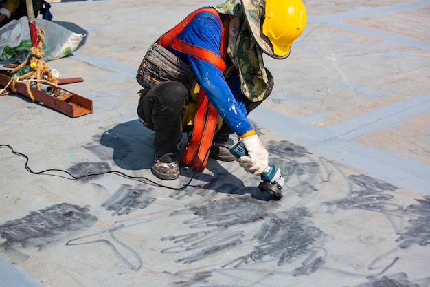 Male worker wearing protective clothing cleaning roof oil storage tank industrial