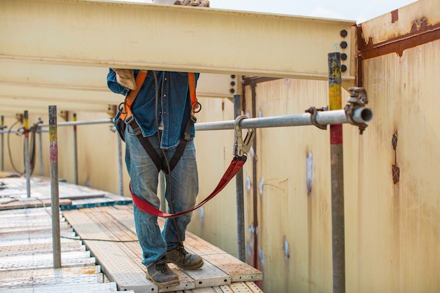 Male worker wearing safety first harness and safety lone\
working at high beam place on top roof tank chemical