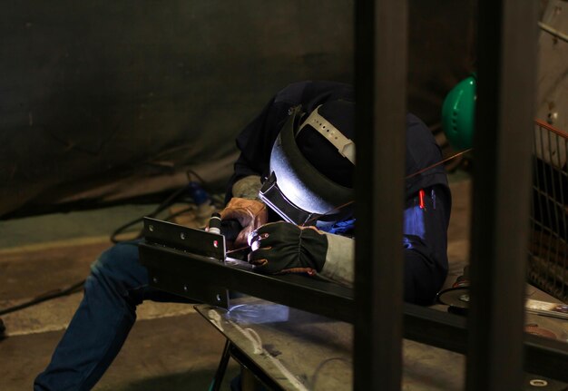 Foto lavoratore maschile che salda metallo in officina