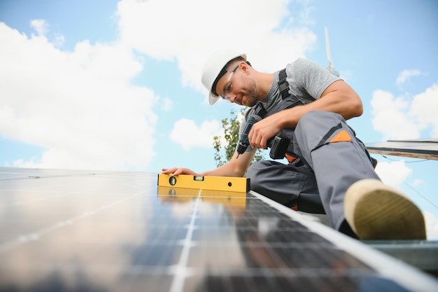 Male worker with solar batteries Man in a protective helmet Installing standalone solar panel system