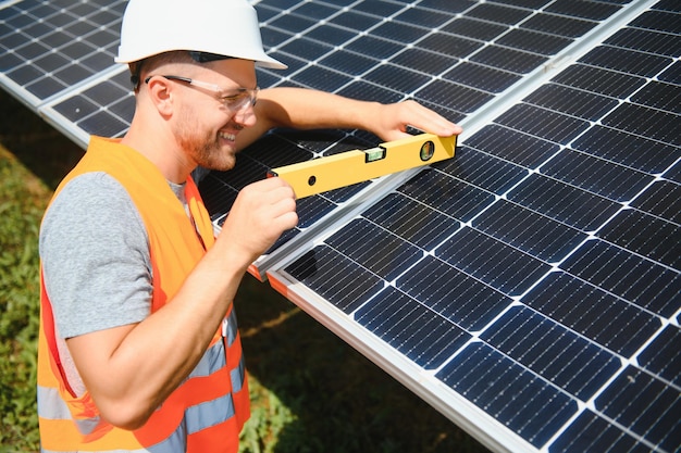 Male worker with solar batteries man in a protective helmet
installing standalone solar panel system