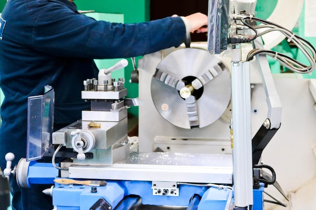 A male worker works on a larger metal iron locksmith lathe equipment for repairs metal work in a workshop at a metallurgical plant in a repair production