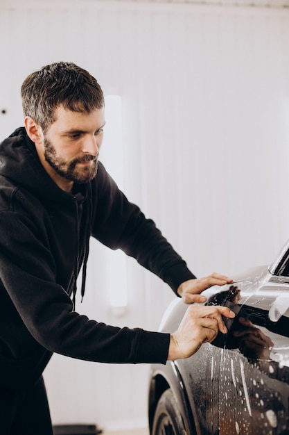 Male worker wrapping car with ptotective foil